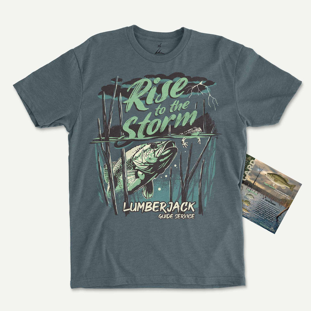 Heather Slate Blue t-shirt with a largemouth bass rising through standing timber under a storm: Rise to the Storm, with its Catch Card
